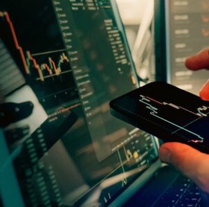 Article graphic asking whether Royal Bank of Scotland customers can still buy cryptocurrency under the FCA's new UK crypto regulations, shown alongside trading charts on a smartphone and monitor.